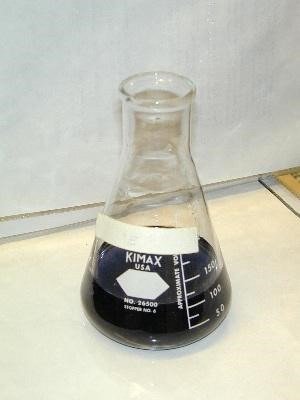 Erlenmeyer flask with dark liquid, chemistry experiment, solvent mixing, laboratory glassware.