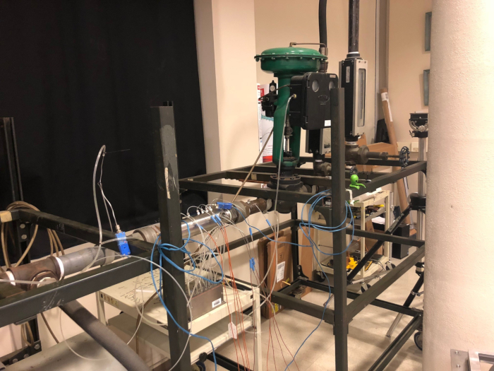 Fluid dynamics lab setup with piping, valves; experiment for flow rate and pressure measurement.
